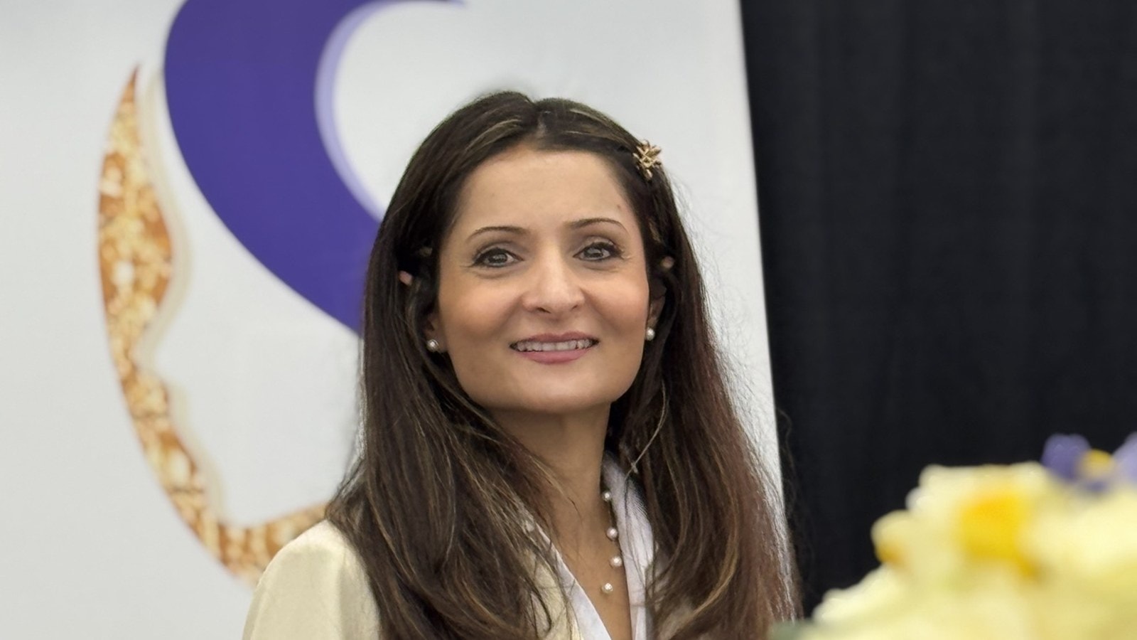 Nastran, smiling, in front of the Nastran Skin Care mark